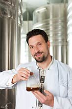 Beer brewer in his brewery examining