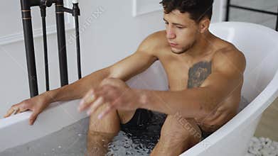 Sportsman gets into a bath with ice cubes