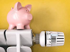 Piggy bank on radiator with radiator thermostat valve. Energy consumption saving concept