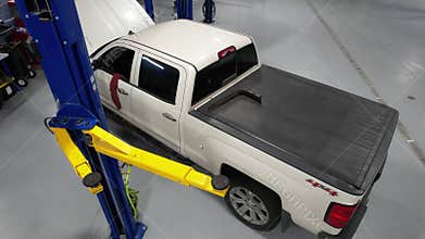 Pickup Truck on an Automotive Lift Inside Authorized Auto Service. Scheduled Car Maintenance.