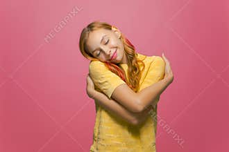 Love yourself. Cute happy girl embracing herself smiling with pleasure, self-acceptance and self-confidence concept