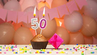 Decorations with balloons and a happy birthday candle with the number 50 for a woman. Happy birthday greetings in pink flowers