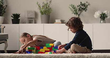 Little boy and girl play plastic constructor in living room