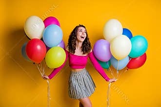 Portrait photo of funny female dreamy teenager looking up wearing casual off-top checkered skirt holding air balloons