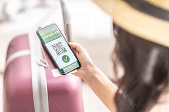 Digital green certificate for international travel displays green Covid-19 vaccinated tick and a QR code in the smartphone of a