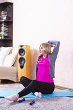 Distant Training Ideas. Tranquil Mature Female While Exercising On Blue Mat During Stretching Session At Home