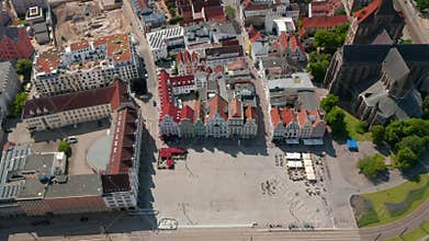Aerial tilt down footage of Neuer Markt square with colourful gabled houses and Saint Mary church. Tram tracks leading