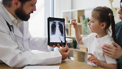 Caucasian doctor showing lung x-ray to young girl in clinic visit