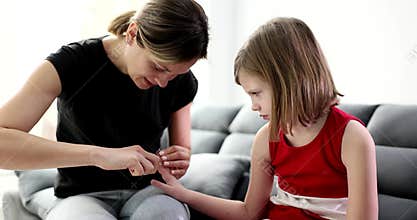 Mom cuts nails of little girl at home