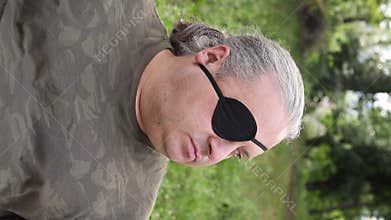 Close-up portrait of a blind, visually impaired man with a black medical patch on his eye