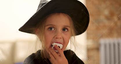 Young Girl Dressed Up as Witch, Complete with Fun Vampire Fangs and Joyful Expression on Her Face