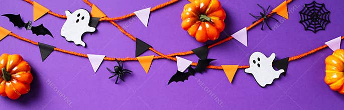 Halloween decor with pumpkins, spiders, ghosts, webs, bunting garland on purple background. Happy Halloween banner design