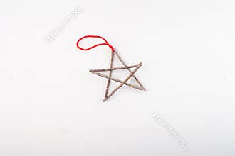 Five pointed star made from twigs, tied at points, red string attached, rustic decoration, festive ornament, plain white
