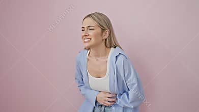 Attractive young blonde woman doubled-over in pain, clutching her stomach. illness evident in her expression, as she stands