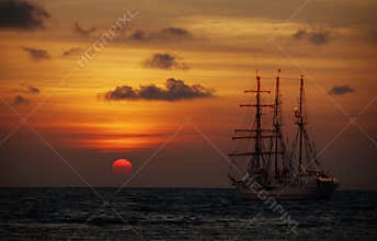 Old sailing ship in the sea at sunset