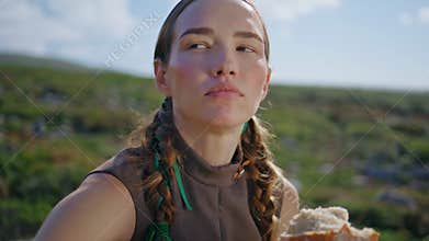 Woman tasting delicious bread on green hill closeup. Countryside girl smell loaf