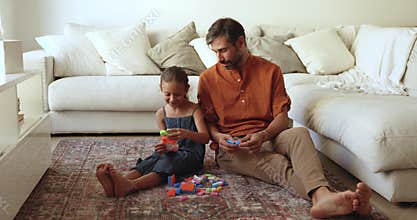 Positive kid girl and middle aged Hispanic dad constructing toys