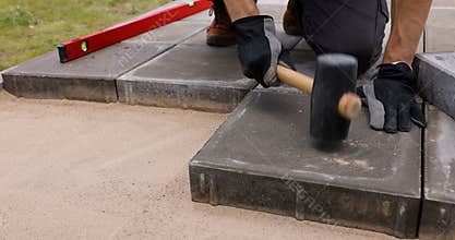 man laying concrete paving slabs with rubber hammer