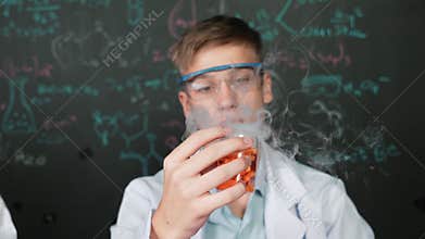 Closeup of boy inspect chemical solution while holding beaker. Edification