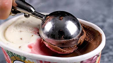 A Metal Ice Cream Scoop Scooping Chocolate Ice Cream From A Tub With Vanilla And Strawberry Flavors
