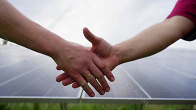 Handshake of two courageous male hands against the background of solar panels.