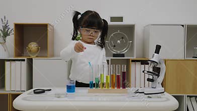 toddler girl scientist study using pipette dropping liquid with test tube and beaker