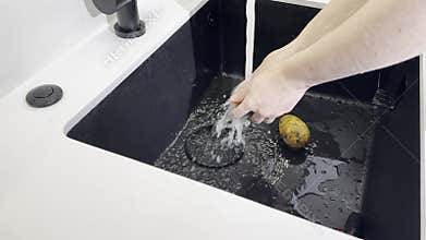 Wash vegetable potato. Hand cleaning fresh potato under faucet water