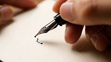 Up close, a hand gracefully wields a fountain pen to script the word Dear in beautiful cursive on a sheet of paper