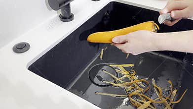 Peel carrot vegetable. Hand holding peeler with blade over sink