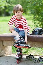 The child put on roller skates on a bench