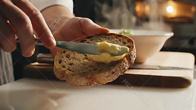 Chef Prepares Pasta Soup with Vegetables Garnishing Plate and Spreading Butter on Bread on Wooden Board Kitchen Countertop