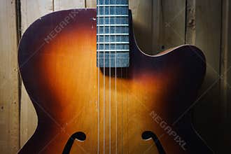 Details of an old jazz guitar on a wooden wall