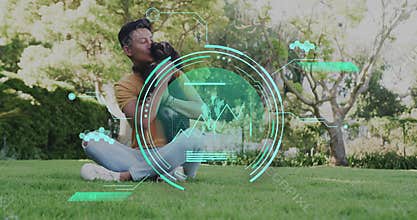 Kissing small brown dog, man wearing mustard tee sitting on garden lawn with holographic interface