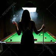 Silhouette of woman smoking cigarette at pool table in dark room