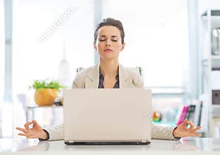 Business woman meditating near laptop