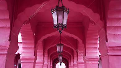 Long pink arched corridor with repeating lanterns hanging from the ceiling