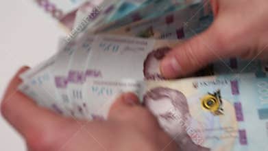 Man hands grab and scatter one thousand hryvnia bills on white podium closeup