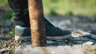 The guy puts his foot on the ground. He puts a baseball bat next to it