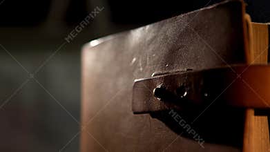 Old leather book with a strap. Stock footage. Close up of an ancient leather brown diary or book with yellow pages
