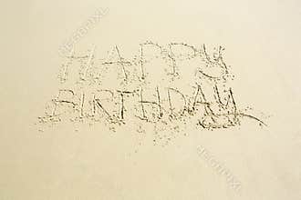 Happy birthday hand written message on wet beach sand