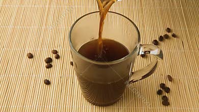 Coffee cup and coffee beans. A white cup of evaporating coffee on the table with roasted bean. Slow Motion coffee pour.