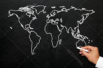 World map on blackboard. A hand draws a stylized globe map of the world with all continents.