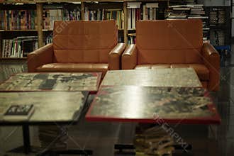 Orange leather chairs in a library with wooden bookcases. Knowledge and education. Blurred