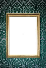 blank golden picture frame hanging on wall on floral vintage wallpaper