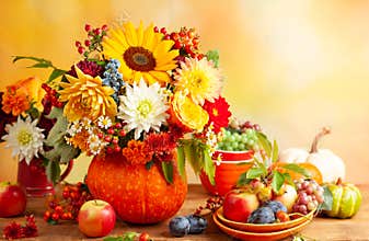 Concept of autumn festive decoration for Thanksgiving day. Autumn bouquet of flowers and berries in a pumpkin on a table,