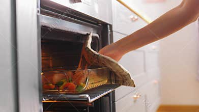 Woman cooking food in oven at home kitchen