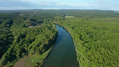 Drone flight above wide river surrounded by green forest