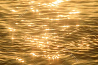 Abstract photo of surface water of sea or ocean at sunset time with golden light tone.
