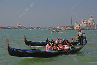 Gondolier rowing oar for tourist gondola in Venice gliding through the Venetian canal with them taking pictures & posing