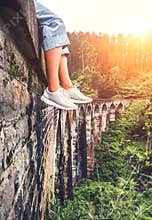 Female tourist sits on the Demodara nine arches bridge in Ella, Sri Lanka: close up feet image